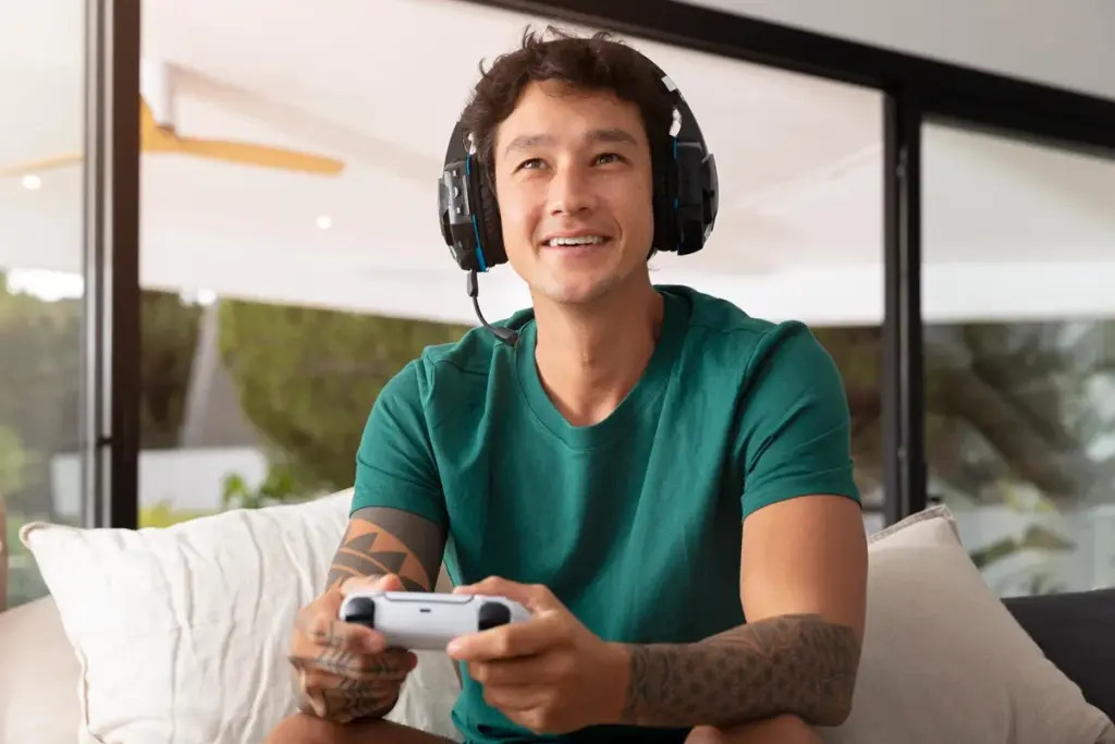 Homem jogando EA FC no Xbox com controle e headset gamer, sorrindo durante a partida.