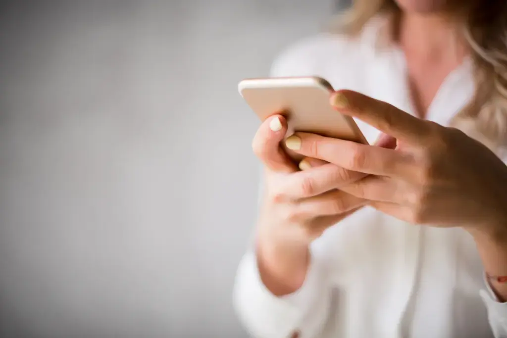 Pessoa segurando um smartphone enquanto utiliza o dedo para interagir com a tela do aparelho.
