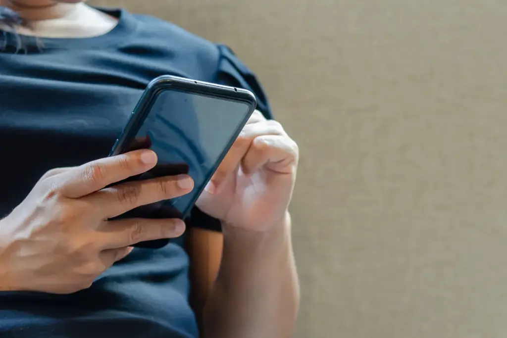 Pessoa segurando um smartphone enquanto toca na tela com o dedo indicador.