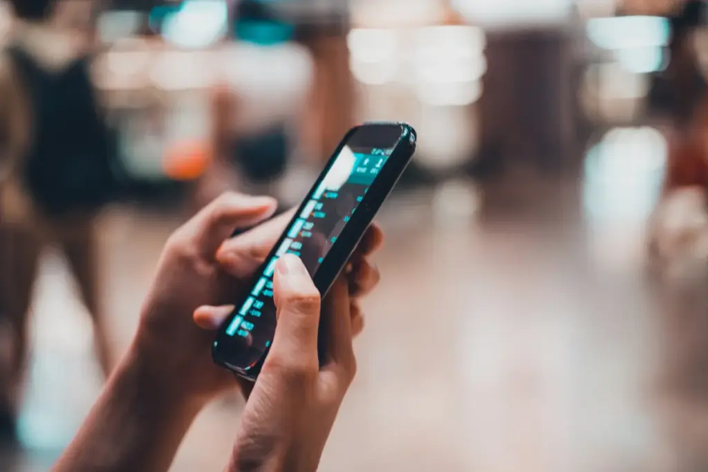 Pessoa segurando um smartphone enquanto navega em uma interface digital exibida na tela do aparelho.