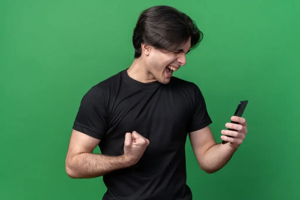 Jogador comemorando ao conferir no celular o uso do Web App e Companion App para gerenciar coins no Ultimate Team no PC