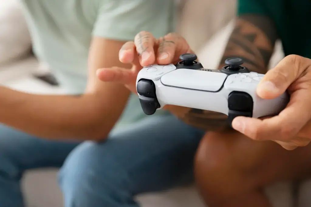Pessoa segurando controle DualSense do PlayStation 5 com as mãos, pronta para jogar videogame.
