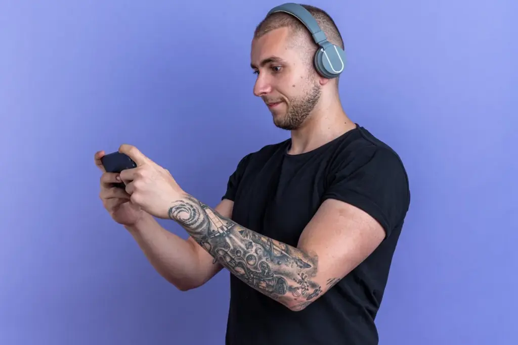 Homem com fones de ouvido jogando no celular em fundo roxo