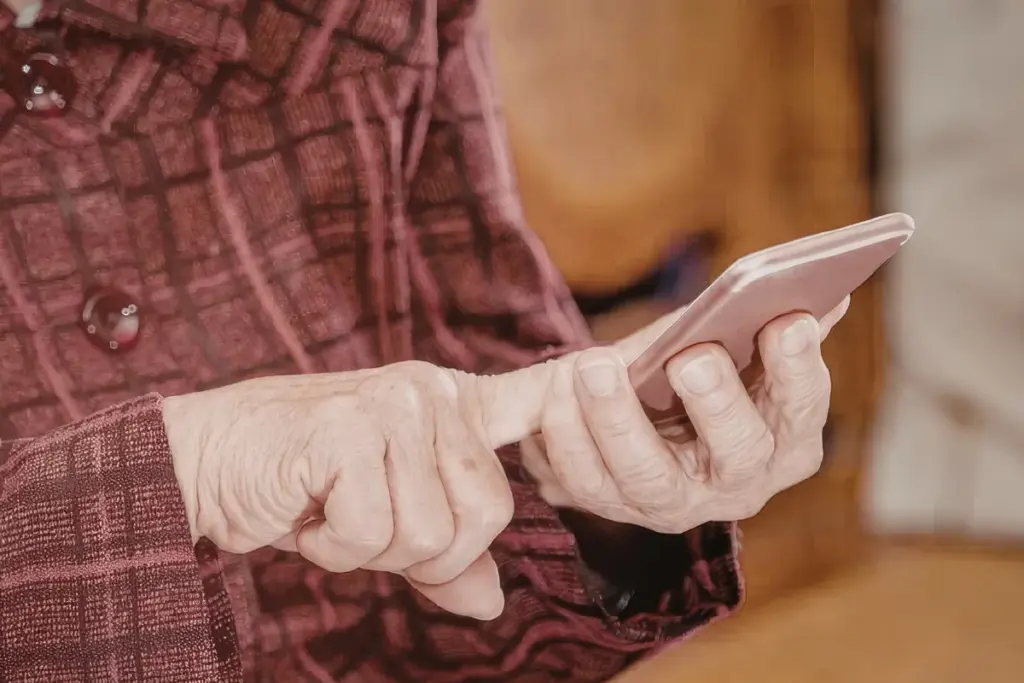Pessoa segurando um smartphone e tocando na tela com o dedo enquanto utiliza o aparelho em ambiente interno.