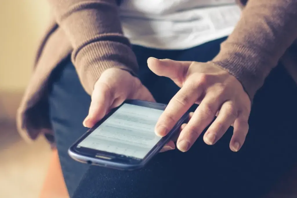 Pessoa segurando um smartphone e tocando na tela enquanto lê uma notificação no celular.